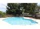 Community pool surrounded by a metal fence, trees, and lounge chairs at 5165 Mystic Point Ct, Orlando, FL 32812