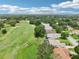 An aerial view shows a manicured golf course lining single-Gathering homes in a lush green community with mature trees at 5453 Grove Mnr, Lady Lake, FL 32159