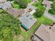 Aerial view of a well-maintained home featuring a light gray roof, manicured lawn, and mature trees at 5453 Grove Mnr, Lady Lake, FL 32159