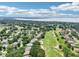 An aerial view showcases homes nestled among mature trees adjacent to a lush green golf course and a beautiful lake at 5453 Grove Mnr, Lady Lake, FL 32159