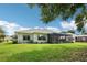 Back exterior of a single-story home featuring a screened lanai and a lush green lawn at 5453 Grove Mnr, Lady Lake, FL 32159