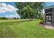 Expansive backyard featuring lush green grass, a large shade tree, and a view of the golf course at 5453 Grove Mnr, Lady Lake, FL 32159