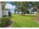 Well-manicured backyard features lush green grass, landscaping, and access to the home's screened lanai at 5453 Grove Mnr, Lady Lake, FL 32159