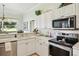 Bright kitchen features white cabinetry, stainless steel appliances, and a double basin sink with a large window at 5453 Grove Mnr, Lady Lake, FL 32159