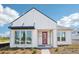 Modern home featuring a crisp white exterior, black awning, and a vibrant red front door at 6723 Sherpa Trl, St Cloud, FL 34771