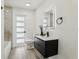 Modern bathroom featuring a black vanity, illuminated mirror, and stylish wood look flooring at 7124 Turquoise Ln, Orlando, FL 32807