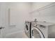 A bright laundry room with a washer, dryer, overhead rack, and a storage cabinet at 921 Costa Mesa Ln, Kissimmee, FL 34744