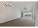 Spacious living area with neutral carpet, a ceiling fan, and sliding glass doors leading to a screened lanai at 10438 Sw 85Th Ct, Ocala, FL 34481