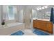 Bright bathroom with a bathtub, a glass-enclosed shower, and warm-toned cabinets at 1124 Hidden Blf, Clermont, FL 34711