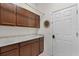 Functional laundry room featuring dark wood cabinets, granite countertop, and a utility sink at 1124 Hidden Blf, Clermont, FL 34711