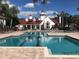 Resort-style pool area with lounge chairs, a large white building, and palm trees in the background at 11582 Westwood Blvd # 1428, Orlando, FL 32821