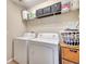 The laundry room has a white washer and dryer with storage shelving above for organization at 11937 Bianca Ln, Orlando, FL 32827