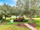 Community playground with mature trees, play equipment, and artificial turf at 11937 Bianca Ln, Orlando, FL 32827