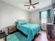 A modern bedroom with a ceiling fan, a blue comforter and teal accents at 13842 Pickett Reserve Ct, Orlando, FL 32826