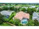 Aerial view showcases home with a terracotta roof, pool, lush landscaping, and community lake at 1453 Langham Ter, Lake Mary, FL 32746