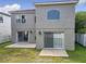 Back elevation view with a tiled patio and access doors, set against a well-maintained lawn and white picket fence at 1803 Meadow Pond Way, Orlando, FL 32824