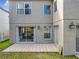 Back exterior featuring a tiled patio, sliding glass doors, and neutral stucco, complemented by outdoor lighting fixtures at 1803 Meadow Pond Way, Orlando, FL 32824
