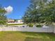 The backyard view showcases a white fence overlooking a serene pond, framed by mature trees and a clear blue sky at 1803 Meadow Pond Way, Orlando, FL 32824