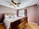 Cozy bedroom features a wood-framed bed, ceiling fan, wood floors, and a window with drapes at 1803 Meadow Pond Way, Orlando, FL 32824