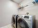Laundry room features modern washer and dryer, tile floor, and shelving unit for storage at 1803 Meadow Pond Way, Orlando, FL 32824