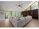 Bright living room with a large sectional sofa, built-in bookshelves, and views of the wooded outdoors at 20 Twelve Oaks Trl, Ormond Beach, FL 32174