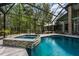 Inviting screened-in pool with spa, surrounded by lush greenery and a spacious patio at 20 Twelve Oaks Trl, Ormond Beach, FL 32174