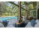 Enclosed pool area featuring a seating area, dining table, pool, and surrounding nature views at 20 Twelve Oaks Trl, Ormond Beach, FL 32174