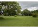 Lush front yard with mature trees, green lawn, and a charming home in the distance, complete with an American flag at 2101 S Goldenrod Rd, Orlando, FL 32822
