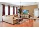 Comfortable living room featuring a tan sofa, wooden floors, an entertainment center, and large windows at 2538 Carter Grove Cir, Windermere, FL 34786