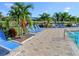 Relax by the pool with multiple lounge chairs and swaying palm trees on a sunny day at 2545 Old Kent Cir, Kissimmee, FL 34758