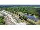 Wide aerial shot of a villa community adjacent to a tranquil pond surrounded by lush greenery and mature trees at 2724 Shelby Ruth Pl, St Cloud, FL 34769