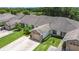 Aerial view of the villa community featuring a paved driveway, lush lawn, mature trees, and neighboring villas at 2724 Shelby Ruth Pl, St Cloud, FL 34769