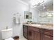 Bathroom with vanity, featuring dark cabinets, granite countertops, and framed mirror at 2724 Shelby Ruth Pl, St Cloud, FL 34769