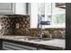 Modern kitchen features a stainless steel sink, granite countertops, and a stylish mosaic tile backsplash at 2832 Buccaneer Dr, Winter Park, FL 32792