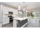 Modern kitchen features white cabinets, stainless appliances, island with a sink and sliding glass doors at 31792 Broadwater Ave, Leesburg, FL 34748