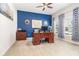Comfortable bedroom featuring a desk with computer, blue accent wall, ceiling fan and natural light from windows at 3349 Sagebrush St, Harmony, FL 34773