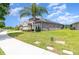 Landscaped gray home featuring solar panels, a well-manicured lawn, sidewalk, and a beautiful palm tree at 3349 Sagebrush St, Harmony, FL 34773