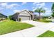 Well-kept home featuring manicured lawn, palm tree, two car garage, and a concrete drive at 3349 Sagebrush St, Harmony, FL 34773