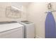 Functional laundry room with washer, dryer, shelving, and ironing board at 408 Southfield St, Kissimmee, FL 34747