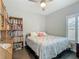 Bright bedroom featuring wood bookcase, ceiling fan, neutral walls, and a comfortable bed with seashell comforter at 439 Lake Daisy Dr, Winter Haven, FL 33884