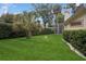Well-maintained backyard featuring a lush lawn, mature trees, and an enclosed patio area at 4823 Shoreline Cir, Sanford, FL 32771