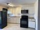 Well-lit kitchen with white cabinetry, black appliances and tiled flooring at 49 Orange Park Blvd, Lake Wales, FL 33898