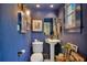 Stylish powder room with blue walls, a pedestal sink, and decorative artwork at 614 Lake Ave, Orlando, FL 32801