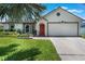 Charming single-story home with an attached two-car garage, a well-manicured lawn, and an inviting red front door at 719 Stevelynn Cir, Winter Garden, FL 34787