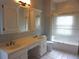 Well-lit bathroom with a double vanity, framed mirrors, and a shower-tub combination behind a sliding glass door at 8025 Old Town Dr, Orlando, FL 32819