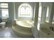 Elegant bathroom with garden tub, decorative arched window, columns, and ceramic tile at 8025 Old Town Dr, Orlando, FL 32819