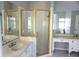 Bathroom with a double vanity, a walk-in shower with a gold frame, and mirrored walls at 8025 Old Town Dr, Orlando, FL 32819