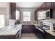 Modern kitchen features stainless steel appliances, granite countertops, and stylish dark wood cabinetry at 936 Calabria Ave, Davenport, FL 33897