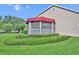 Charming screened porch with a bright red awning, set amidst lush, manicured landscaping at 104 Nautica Mile Dr, Clermont, FL 34711