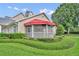 Inviting home with a charming screened porch, a bright red awning, and meticulous landscaping at 104 Nautica Mile Dr, Clermont, FL 34711